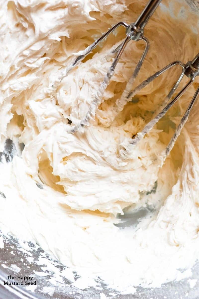 top view of buttercream frosting in bowl with whisks