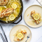 chicken topped with onions, garlic, and lemon on two plates