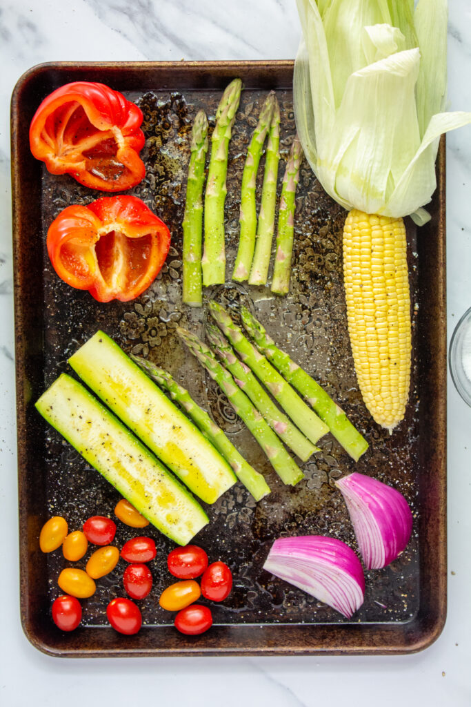 sliced and seasoned vegetables on baking sheet