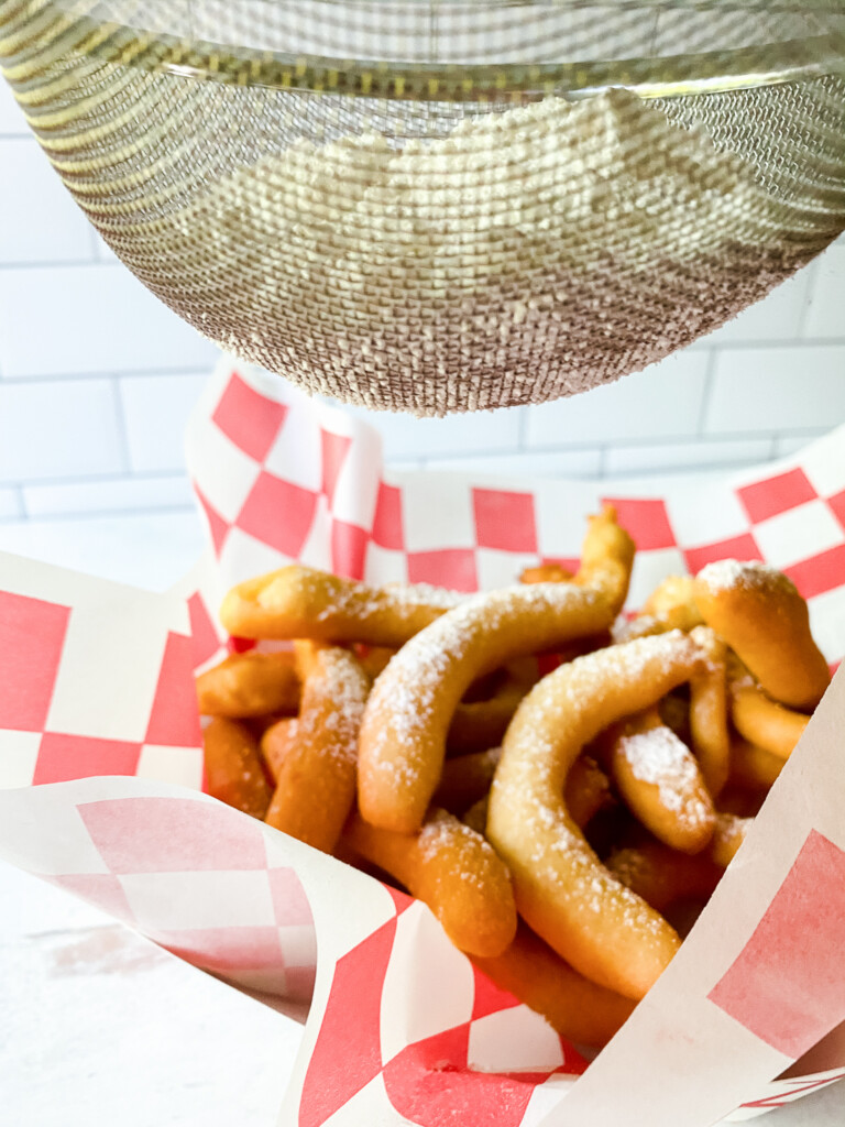 funnel cake fries being dusted with sugar
