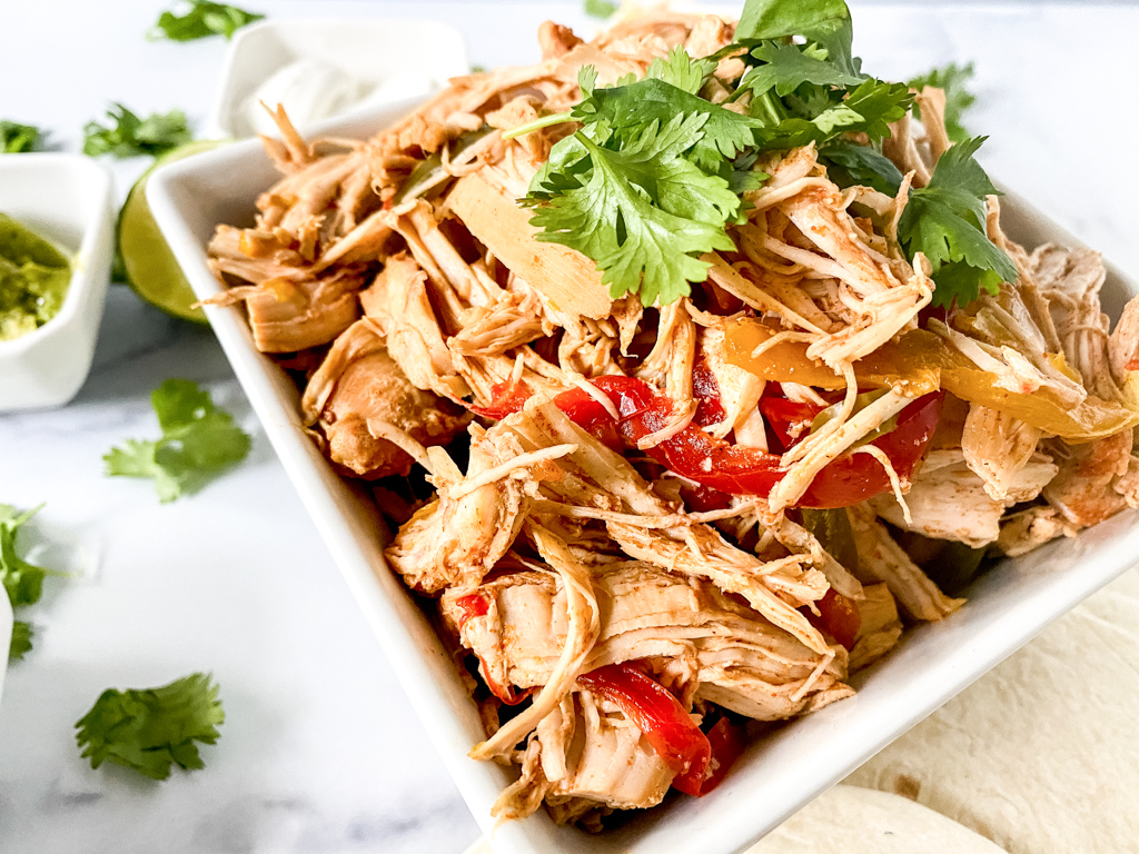 Crockpot chicken fajitas on bowl with cilantro and peppers