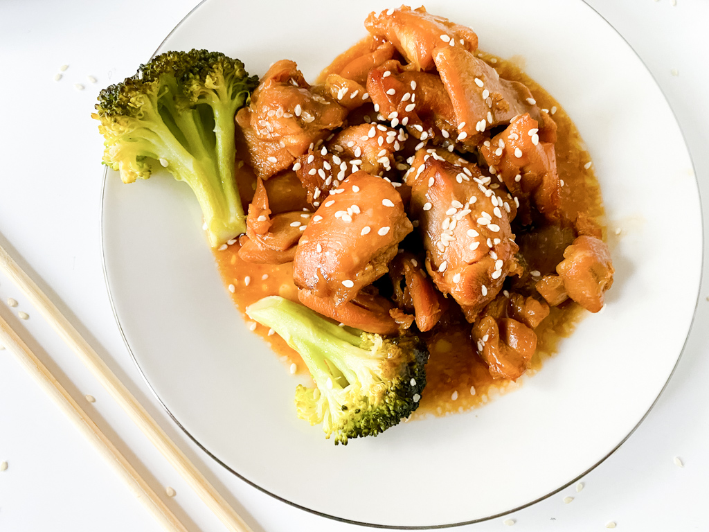 broccoli and crockpot sesame chicken on white pate with chopsticks