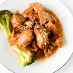 crockpot sesame chicken on white plate with broccoli and sesame seeds