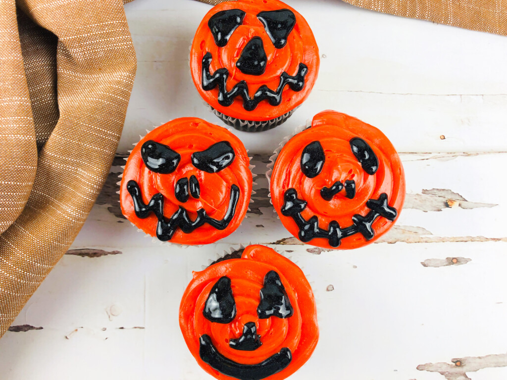 top view of jack o lantern cupcakes with black and orange frosting